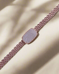 Rose gold bracelet with diamond-encrusted clasp on a beige fabric background