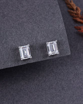 Pair of emerald-cut stud earrings on a gray surface
