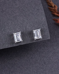 Pair of emerald-cut stud earrings on a gray surface