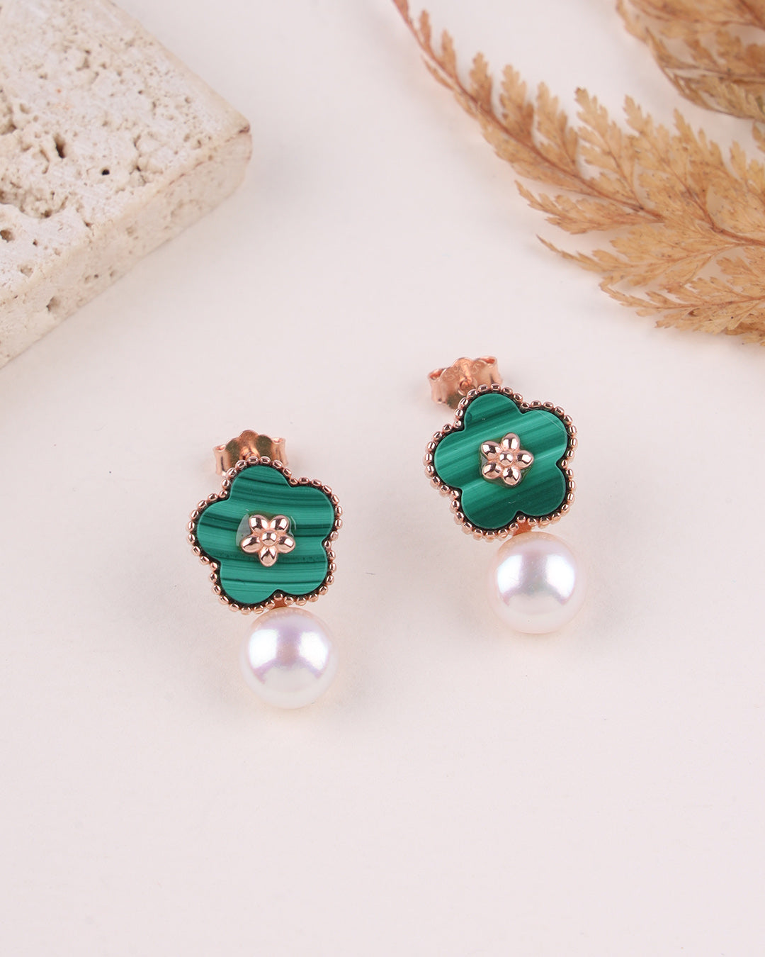 Green floral earrings with rose gold accents on a light background