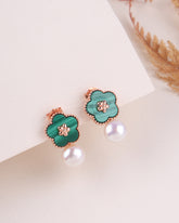Pair of green floral earrings with rose gold accents on a white surface.