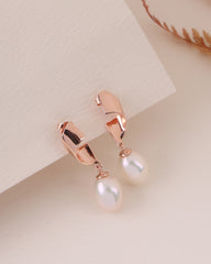 Rose gold earrings with pearl drops on a light background