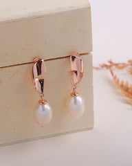 Rose gold earrings with pearl drops on a wooden box