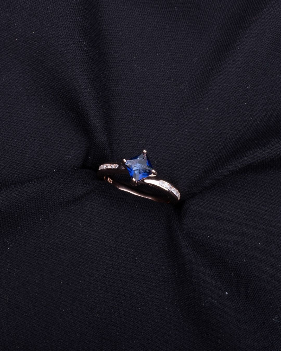 Silver Ring with a blue gemstone on a black fabric background