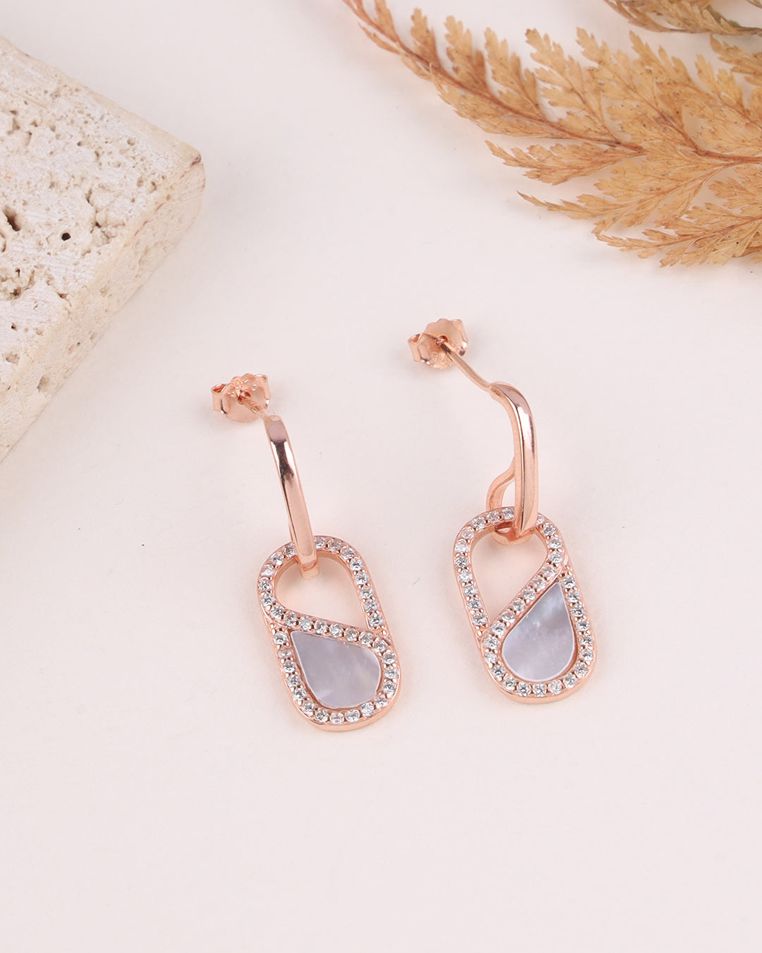 Rose gold earrings with MOP on a light background