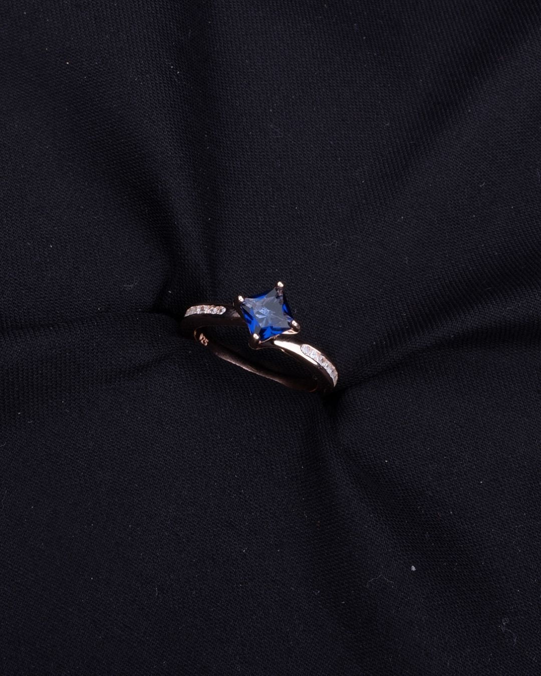 Ring with a blue gemstone on a black fabric background