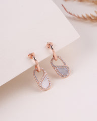 Rose gold earrings with clear gemstones on a light background