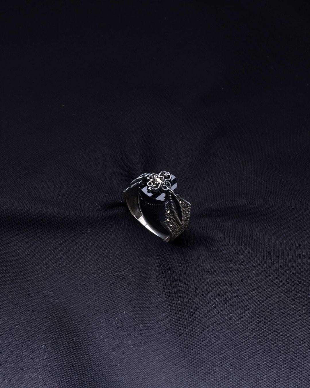 Silver ring with a diamond on a black fabric background