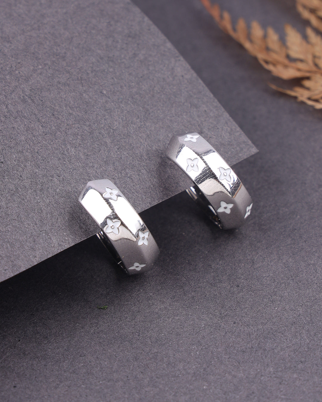 Silver earrings with geometric design on a gray surface