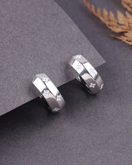 Silver earrings with geometric design on a gray surface