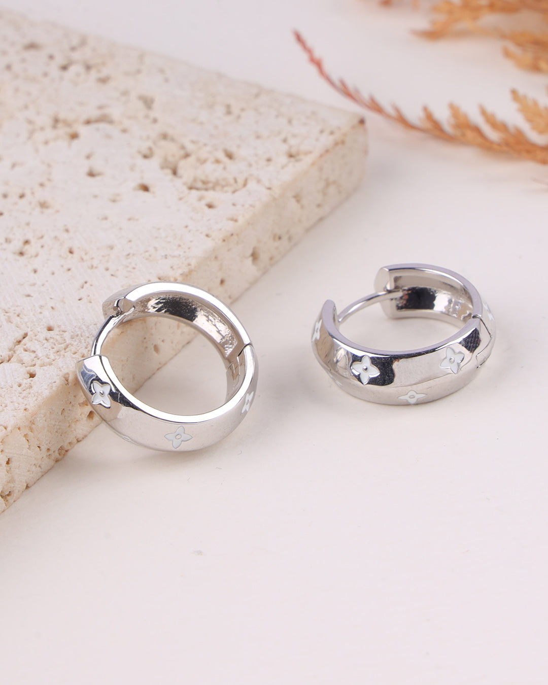Silver hoop earrings on a light stone surface