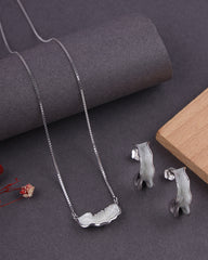 Silver necklace and earrings on a dark surface with a wooden block
