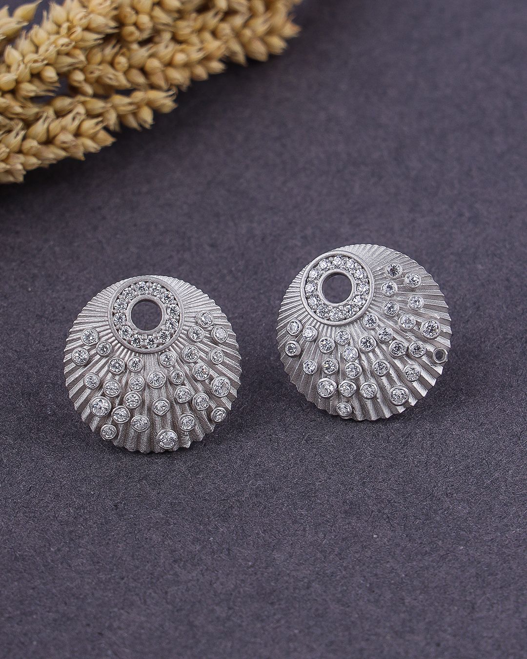 Silver earrings with intricate designs on a dark surface