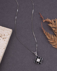 Silver necklace with a flower pendant on a dark surface