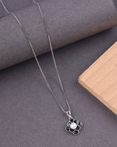 Silver necklace with a pendant featuring a pearl on a gray surface.