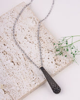 Necklace with textured pendant on a stone surface