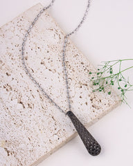 Necklace with textured pendant on a stone surface
