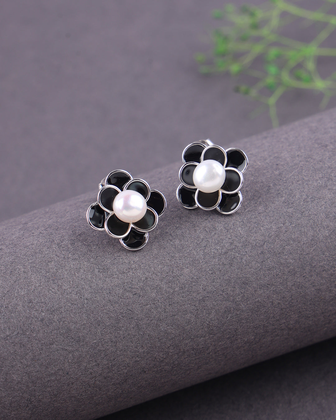 Flower-shaped earrings with pearls on a gray surface