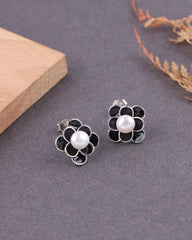Flower-shaped earrings with pearls on a gray surface