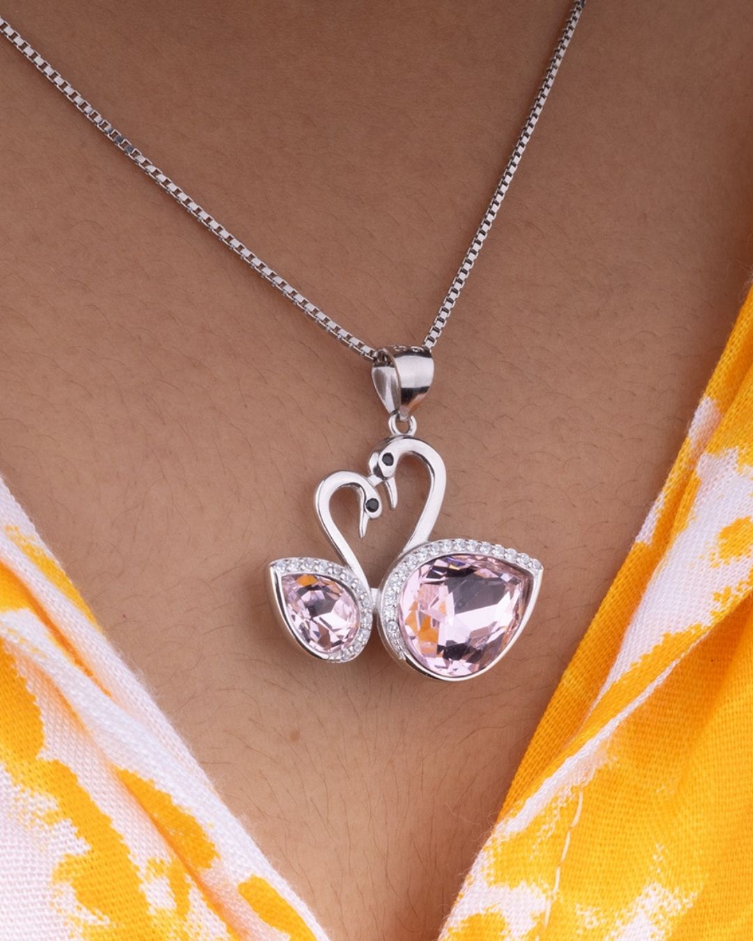 925 Sterling silver Necklace with a swan-shaped pendant featuring pink gemstones on a person wearing a yellow and white patterned garment.