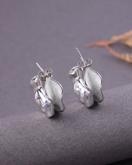 Silver leaf-shaped earrings on a gray surface