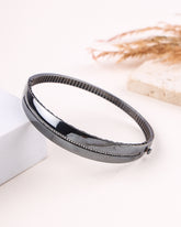 Black silver bracelet on a white surface with a blurred background