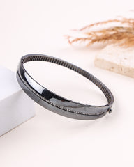 Black silver bracelet on a white surface with a blurred background