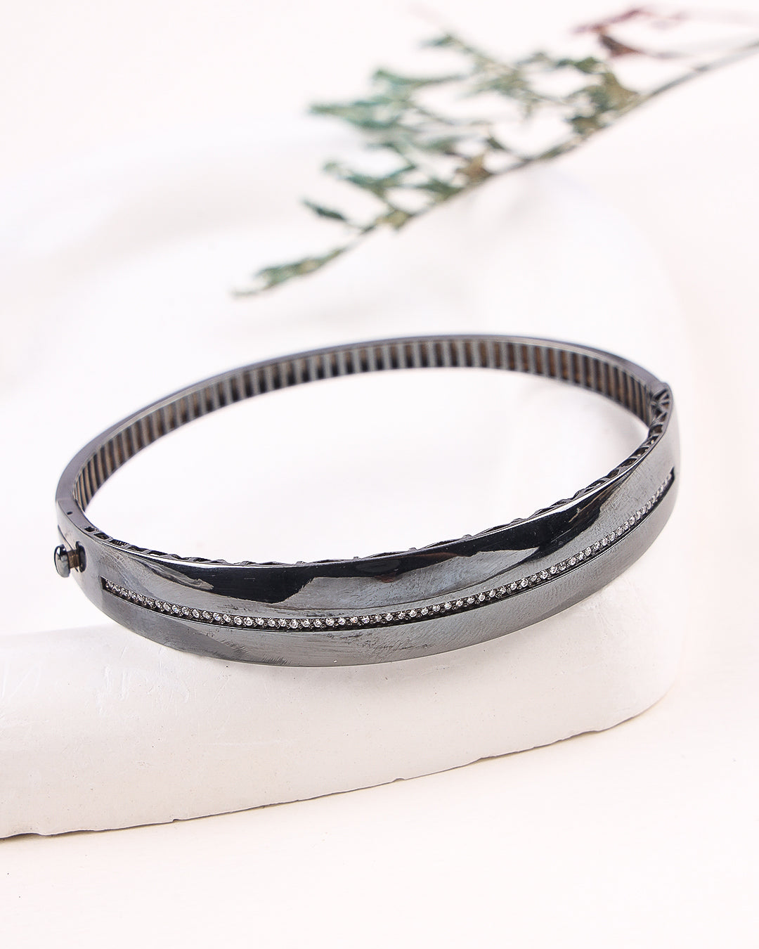 Black bangle on a white surface with a floral background