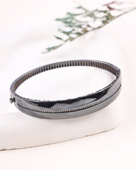 Black bangle on a white surface with a floral background