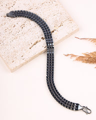 Black braided bracelet on a light stone surface