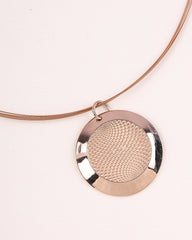 Rose gold necklace with a textured round pendant on a light beige background