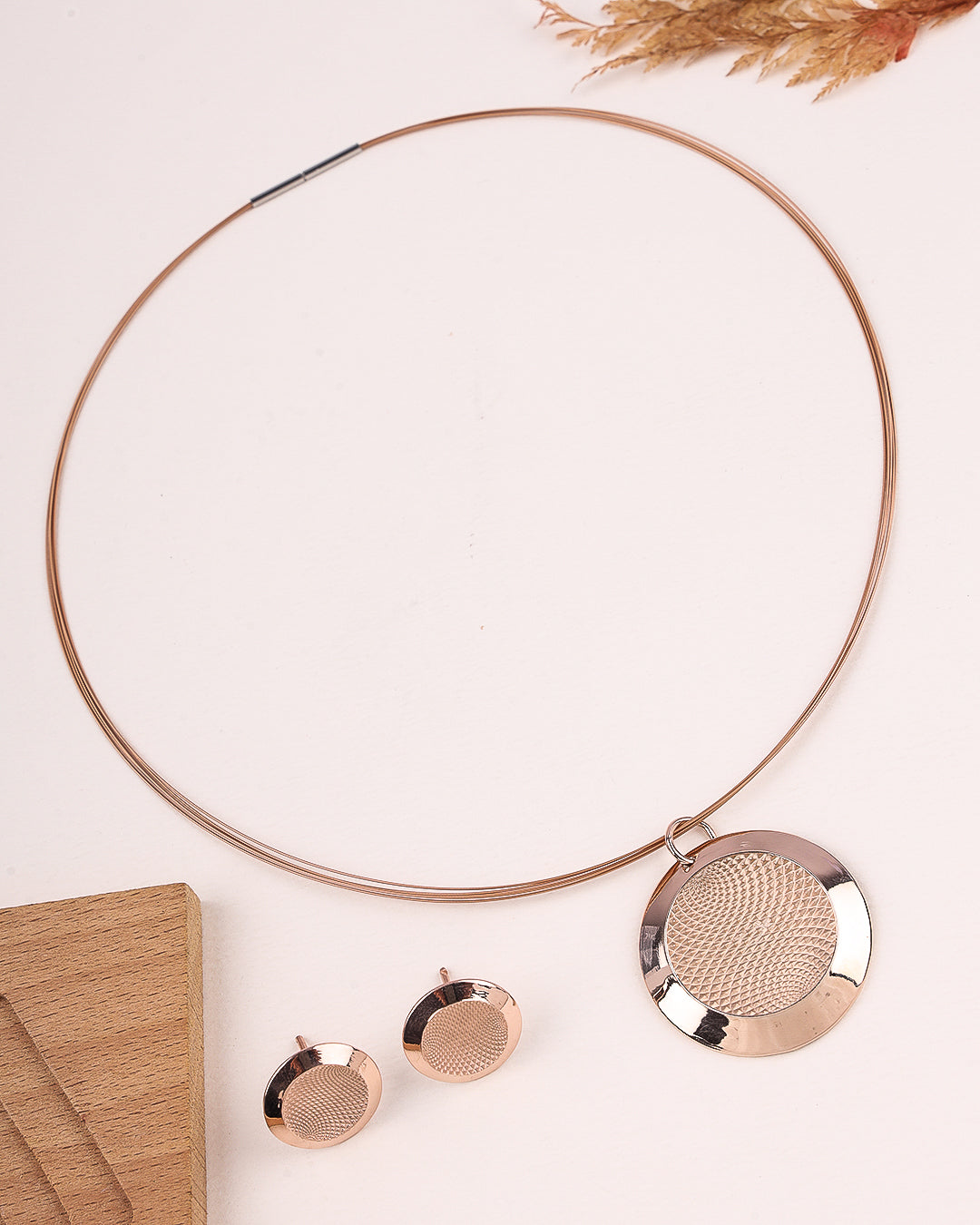 Rose gold necklace and earrings on a light pink background