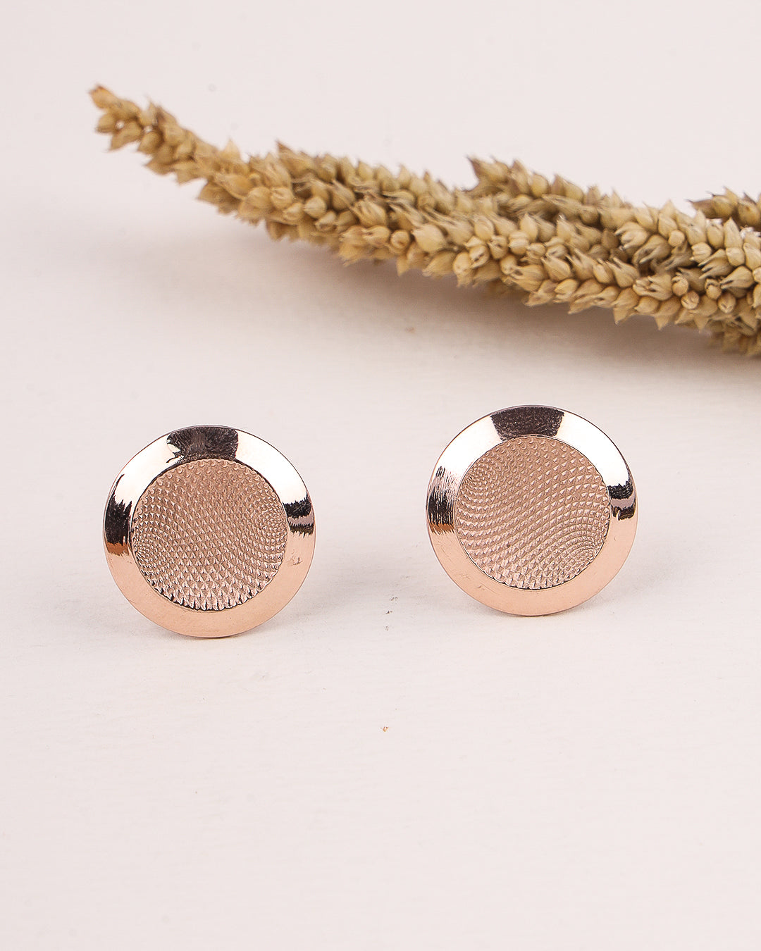 Rose gold earrings on a light background with dried lavender.