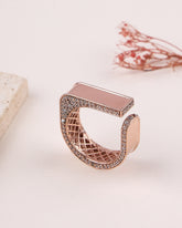 Rose gold ring with intricate design on a light background
