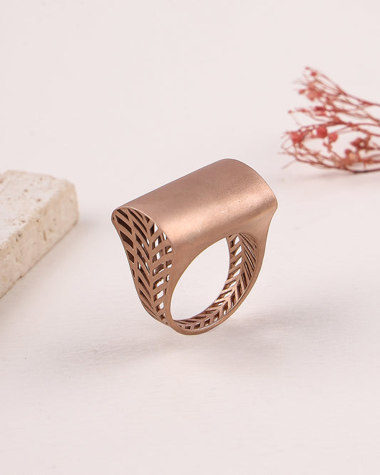 Rose gold ring with intricate design on a light background
