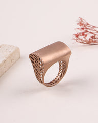 Rose gold ring with intricate design on a light background