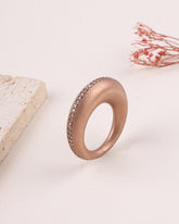Rose gold ring with embedded stones on a light background