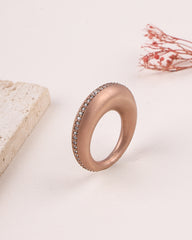 Rose gold ring with embedded stones on a light background