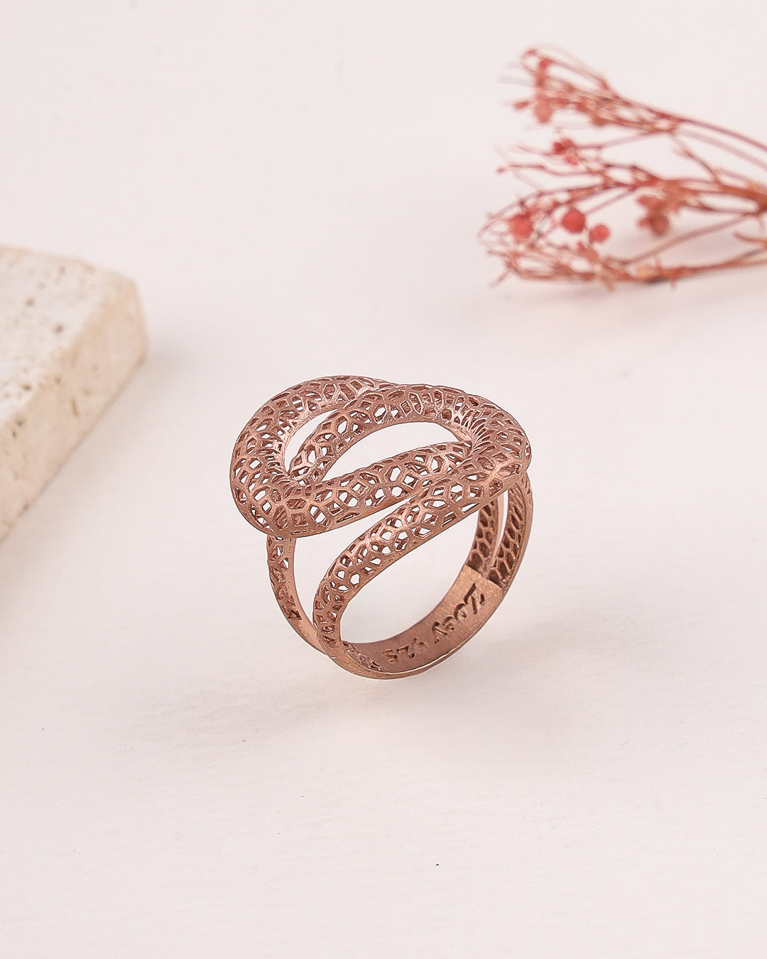Rose gold filigree ring on a light background