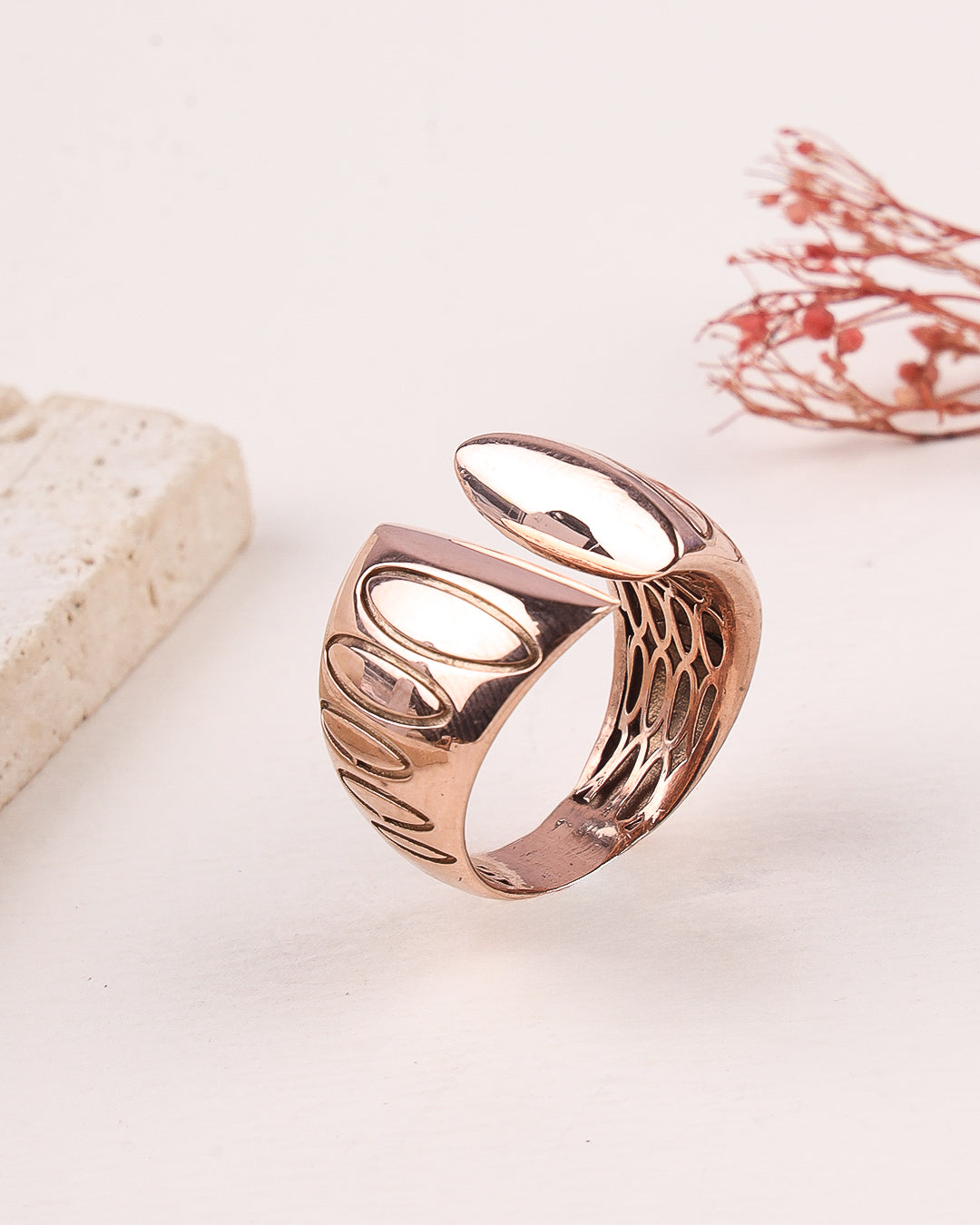 Rose gold ring with intricate design on a light background