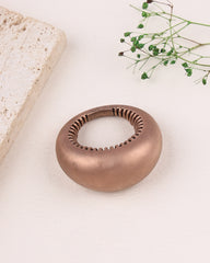 Rose gold silver ring on a light background with greenery