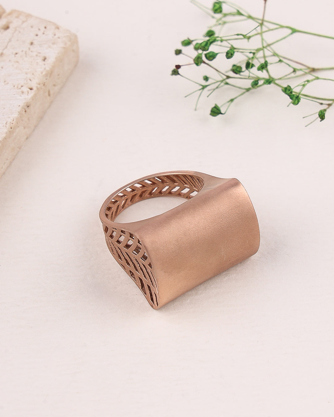 Rose gold ring with intricate design on a light background