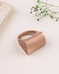 Rose gold ring with intricate design on a light background