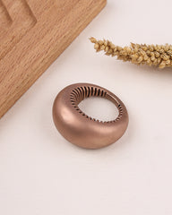 Rose gold silver ring with a textured design on a light surface.