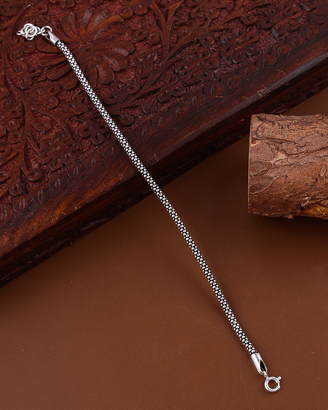 Silver chain necklace on a textured brown surface