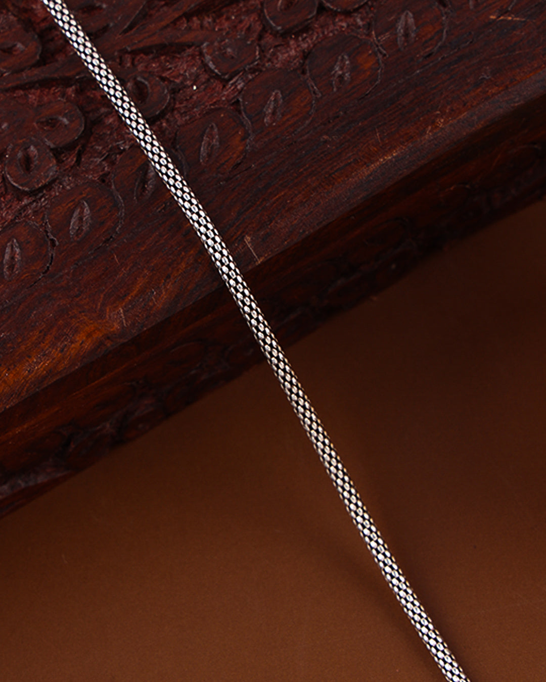 Close-up of a braided cord on a textured brown surface