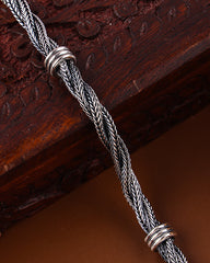 Silver braided cord with decorative ends on a wooden surface