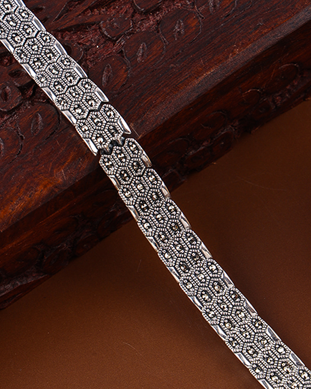 Silver bracelet with intricate design on a wooden surface