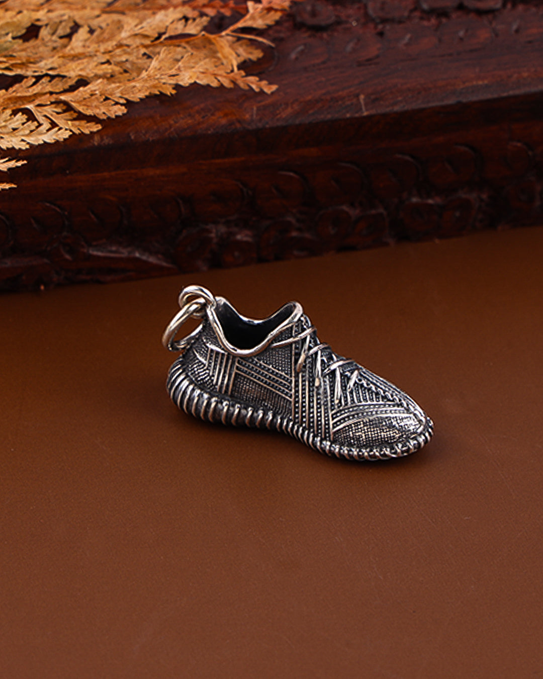 Silver shoe charm on a brown surface with wooden background