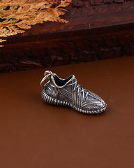 Silver shoe charm on a brown surface with wooden background
